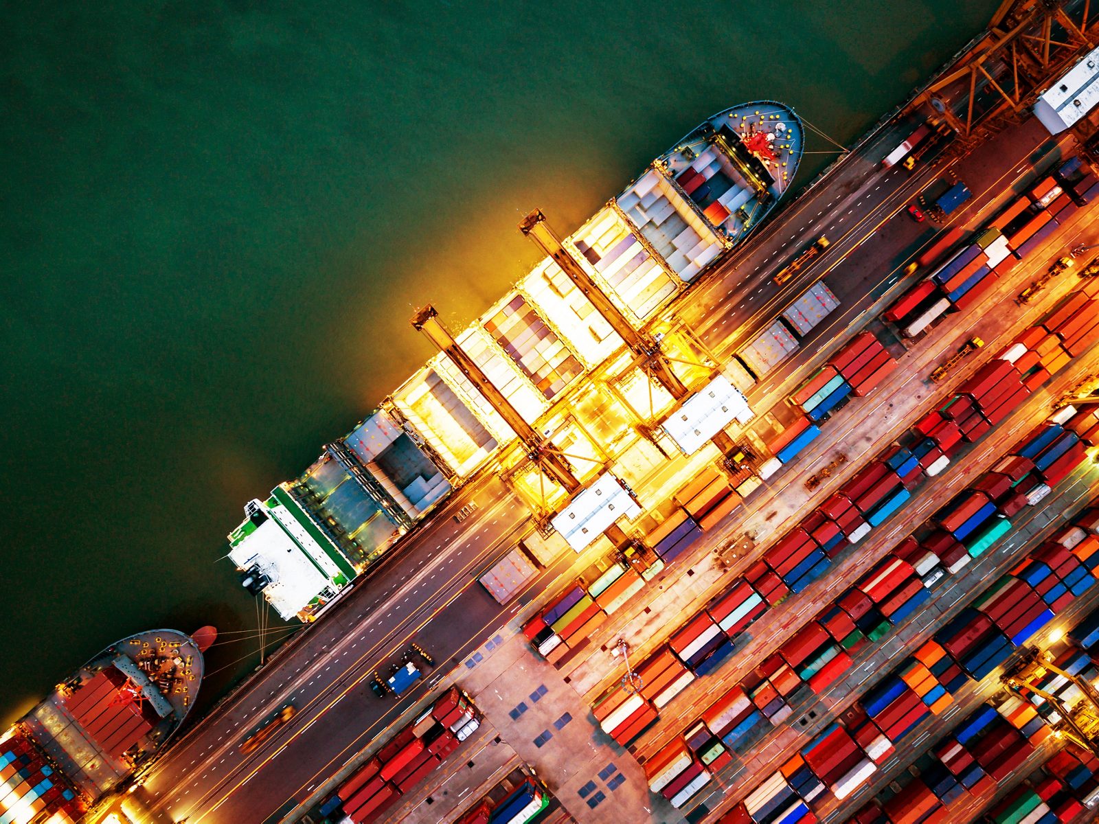 Top view of international port with Crane loading containers in import export business logistics at night.